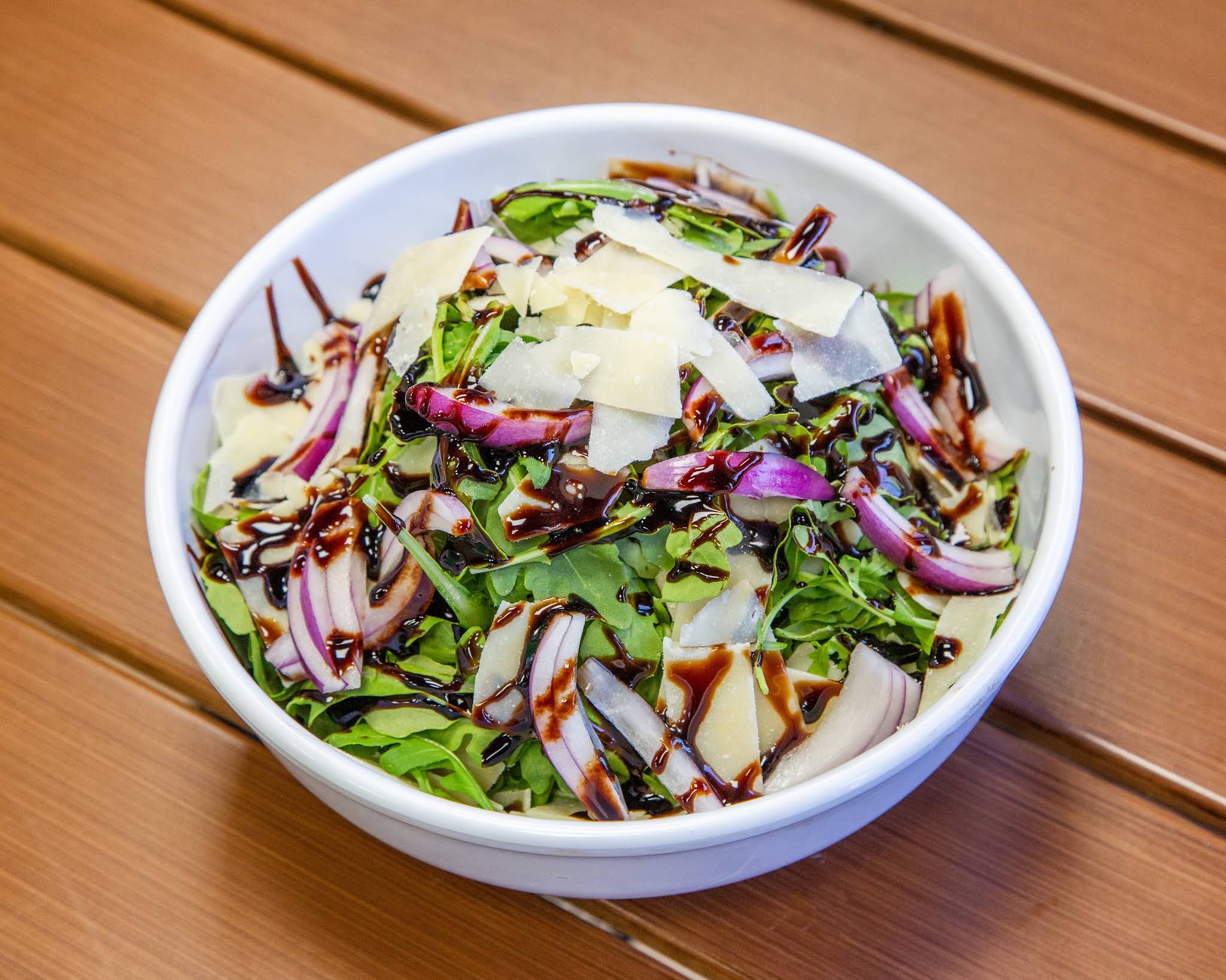 Arugula salad with shaved cheese, red onion and dressing at Terrible Eddie’s