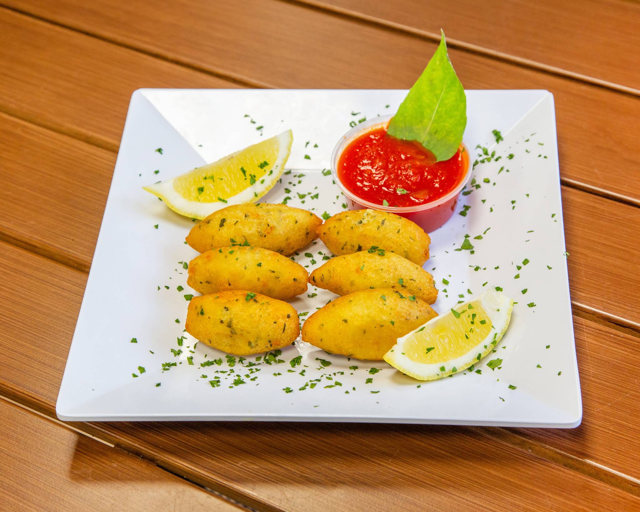 Golden croquettes served with red sauce and lemon at Terrible Eddie’s